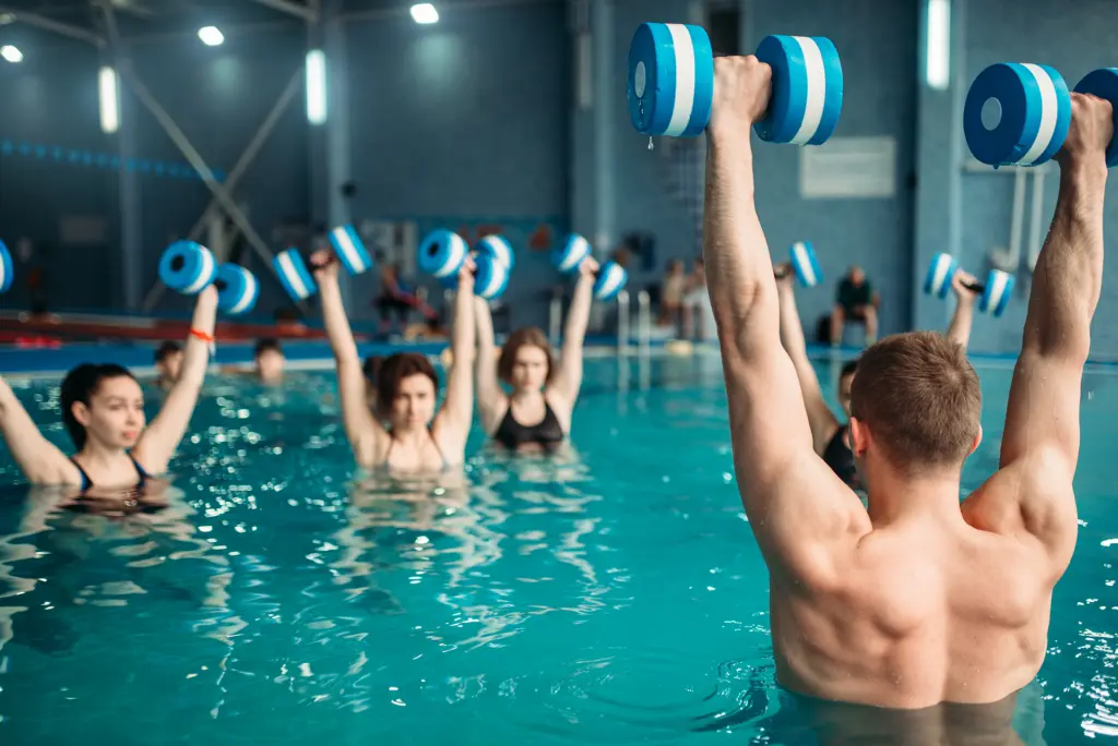 standing-office-yoga-workout-workout Aquafitness-Gruppe im Schwimmbad trainiert mit Wasserhanteln über dem Kopf