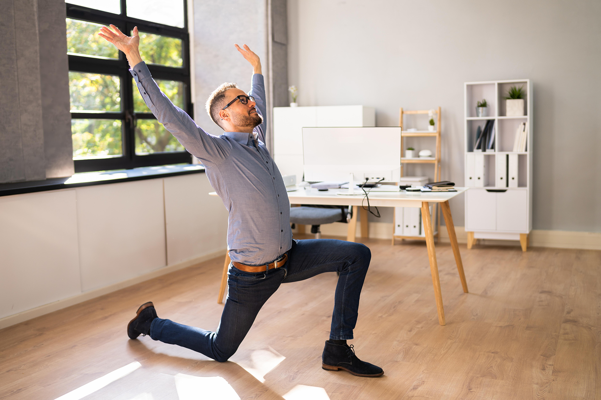 Büro-Yoga Mann im Hemd dehnt sich im Büro im Ausfallschritt mit erhobenem Arm